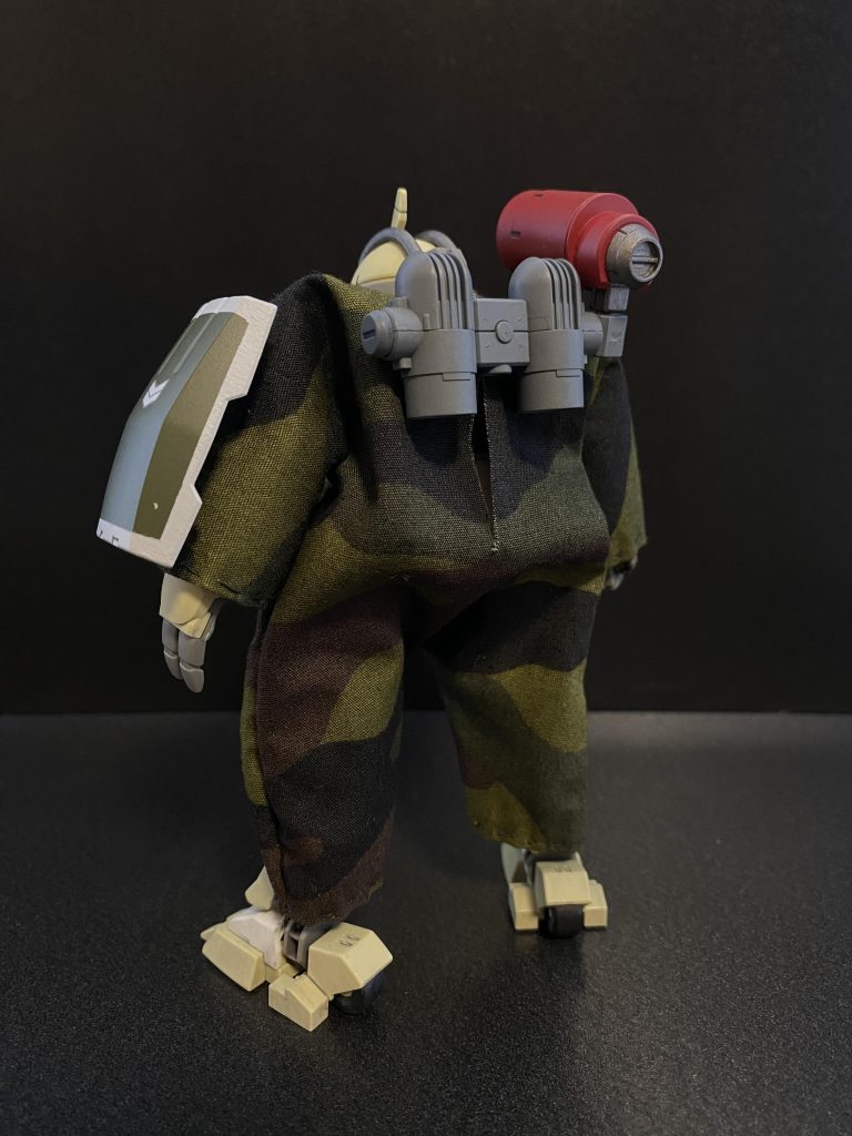 　地球寮の生徒らによって開発されたパジャマ。いや、MS用迷彩服。デミトレーナー専用の装備品として複数着が学園に寄付されている。訓練時の使用も可能である。　非常に高い防塵性能を持つ。始めは全身を覆う構造上、機体の可動域の低下と言う問題があったが、採寸の際、サイズを大きくすることにより着用時の可動域に余裕を持たせている。その為、着用時のシルエットはややずんぐりとしたものになっているが、一部の生徒からは好評のようだ。　また、機体のほぼ全面を覆う構造上、放熱に対する問題もあったが、より通気性の高い生地を使用することで解決している。　あくまで、「布」であることから、様々な「柄」を用意することができる。