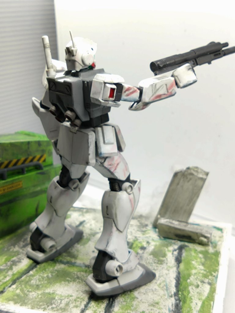 後ろ姿。ジオラマベースの地面(コンクリート製だと思うのですがアニメでは緑色なんですよね)は最初スタイルホームにアクリル絵の具で手描きしてみましたが、質感出なくてカッコ悪い。そこでホームセンターでコンクリート補修剤壁用ってやつ(一番安かったやつ)を買って塗り硬化まで待てなくて水性カラーで色付しました。建物は１００均購入のスチレンボードをセメダイン接着で組立しました。やっと少し質感良くなりました。😅