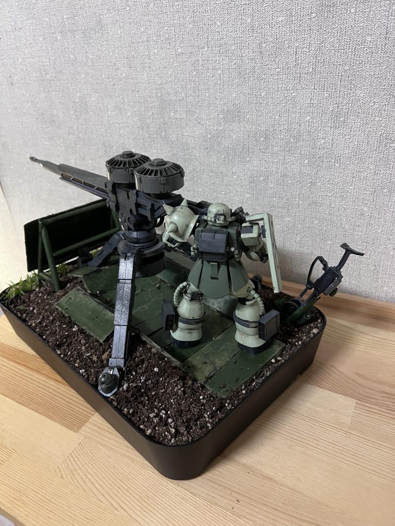 バックからです。地面はオヤジの趣味の家庭菜園から拝借して、プレートは段ボール、組んである鉄パイプは100均のクラフト用ストローを使用してます。ザクマシンガンラックもこれで作成しました。