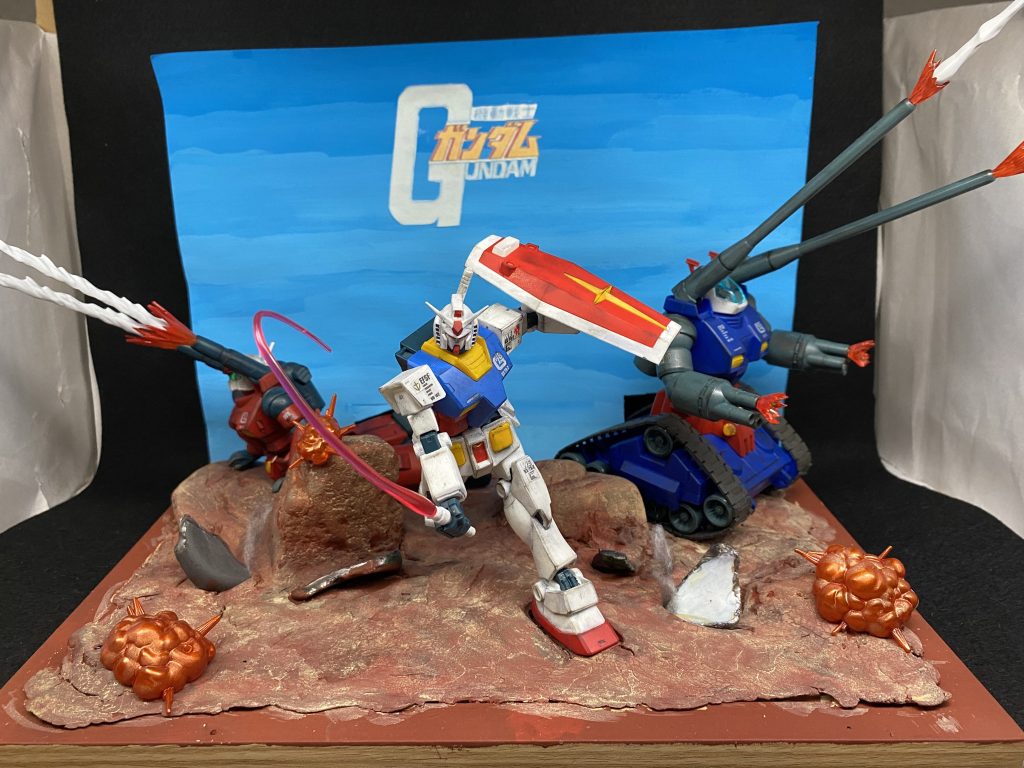 上から。土台はDAISOのフレーム。地面は同じくDAISOの木粉粘土にアクリル絵の具とウェザリングカラーのサンド,ウェザリングマスターで塗装しました。岩と散らばってる地上戦艦の破片をイメージした金属片は河原で拾ってきた石とビンの破片を塗装しました。また背景はアクリル絵の具で空描いてそこに印刷した1stのロゴを貼り付けました。