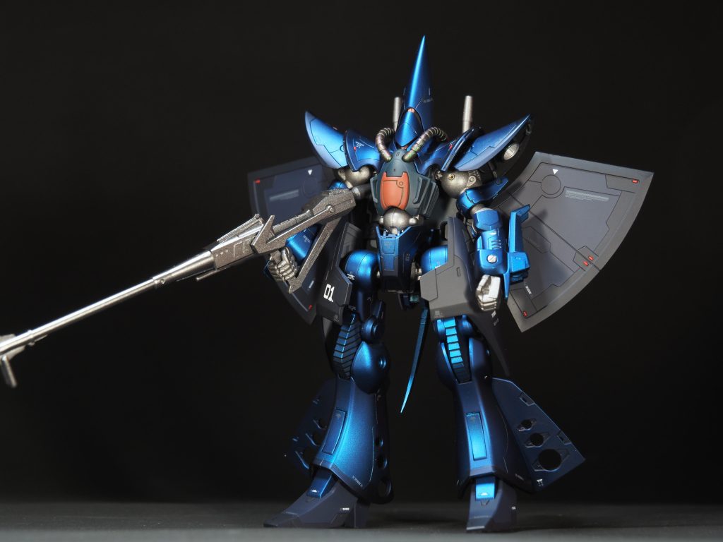 今回は、つや消しキャンディ塗装に挑戦してみました。下塗り、シルバー、クリアブルー、つや消しと、かなり塗装工程が多く大変でしたが、いざ出来上がってみるといい感じのメタリックマット感が出て自分としては大満足の仕上がりです。シルバーはクレオスのラフシルバー、クリアブルーはガイアノーツのクリアブルーを使いました。ただ、青の深みが足りなかったので、4コート目にクリアブラウンを少し混ぜて、彩度と明度を少し落としました。縁の濃い部分はクリアブルー+クリアレッドを載せてあります。成型色で紺色の部品はソリッドカラーにつや消しで仕上げました。ちなみに、画像では目立ちませんが、エネルギーチューブにセ○アの偏光ネイルパウダー(緑ピンク)を使いました。ショルダーアーマーの中がスカスカで寂しかったので、スラスターとゲショゲショ感を追加してあります。