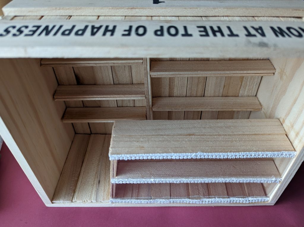 そこに園芸コーナーに売っていた植木鉢に花の名前を書いて刺すような木の棒を切ってボンドで貼って穴を埋めて棚を作っていきます。カウンターもセリアのプラバンとレースです。