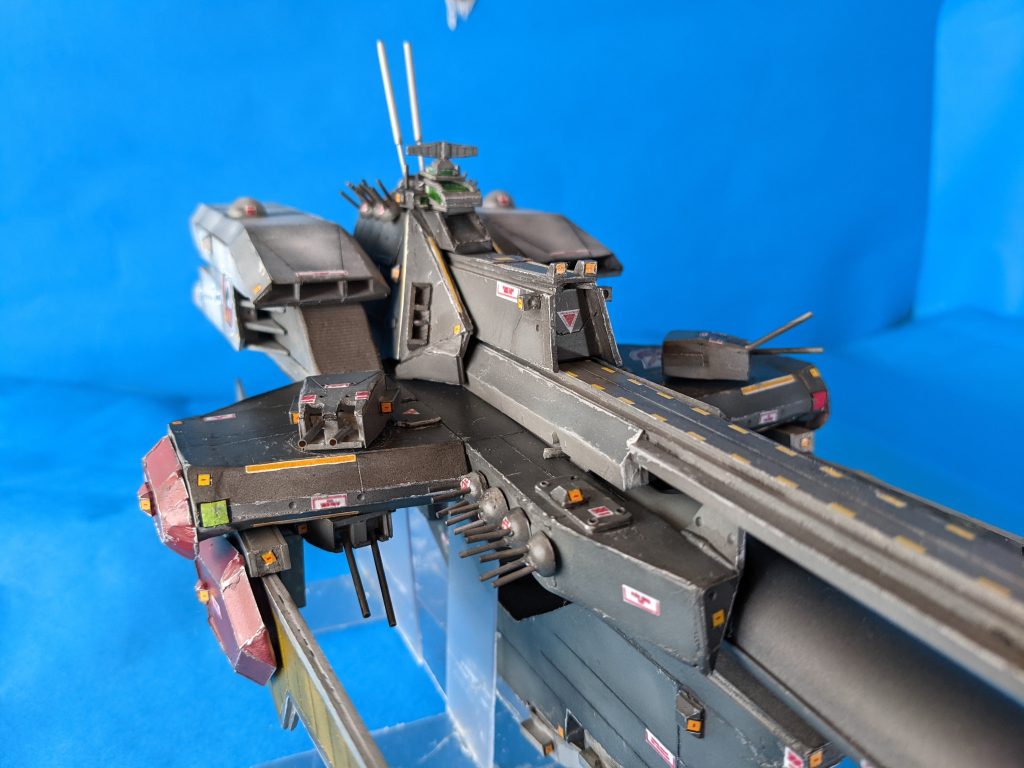 ガンプラは一年に一度しか創らない方のKino.pです。今回は初挑戦のフルスクラッチ、1/1200スケール『リーンホースJr.』です。設定画の三面図をCAD使って縮尺を1/1200に合わせてバランス見てから図面引く、（この工程で二日）そんなところから始めました。そのかいあってバランスは破綻してませんね。さすがに1mm単位でパーツを創る精度がなく、1mm、3mm、5mmのプラ板、プラ棒に合わせてパーツは作成しています。その為、誤差±5mmくらいの精度です。全長は約422mmの大型キットになりました。ガンプラを改造してこちらのサイトにアップするようになって三年目。なんとかフルスクラッチもどきが創れるようにはなりました。 …ちょっとだけ、この作品に込めた話にお付き合い下さいますか？お時間は取らせません。 「フルスクラッチ！？自分には無理だよ」って思ってました。今回もテキトーに旧キットを改造しアップしようかと思いました。でも、ね。昨年六月。いつものように『旧キットマゼラン』を作っていたら。私の大好きな漫画家が死にました。何一つ不自由のない、そんな人でも簡単に死んでしまうんですね。私は大切な事は全てガンダムとマンガとアニメから教わりました。私の好きな主人公（やはり作者は他界）が言うんです。「それとも お前　何十年も修行して達人にでもなるのを待ってから戦場にでるつもりか？気の長げぇ話だな。…だったら　今手持ちのコマでやりくりするしかねぇだろ。」明日があるかなんて分からない。だから、今のスペックで、持てる最大限のスペックでどんなにみっともなくても良いから、私は私の戦場に出ようと。「いつか」創りたいと思っていた大好きな『リーンホースJr.』を「今」創ろう、と。熱意だけでプラ板とプラ棒に「いくつもの愛を重ねて」突っ走りました。この半年、『リーンホースJr.』がこの手の中で形になっていくのが物凄く楽しかったですね。どの場所を切り抜いてもめちゃくちゃ楽しい濃密な時間でした。 だから胸を張って言います。「見て下さい！」