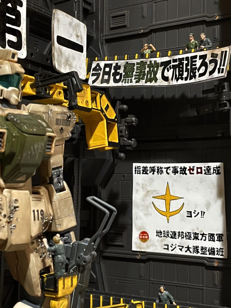 上方から様子をみているのは小隊長のゴトー、整備班長ミスターサカキ、現場監督のシバという名前をつけました。特車二課第二小隊ではなく、コジマ大隊第02小隊とかです。でも作りながら観てたのは、某劇場版2です。下の看板のヨシ！まで書いて例の猫を描く寸前で踏みとどまった自分を褒めてあげたい。でも、そのせいか、少し寂しい看板に。後でこっそり描こ。上の標語は旗っぽくするため少し曲げて布感を出したかったんですが、厚みが出ちゃいました。プラバンをもっと薄いものにすればよかった。