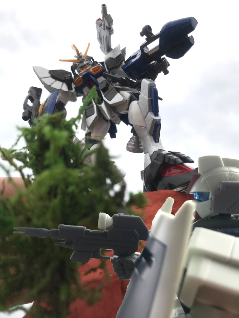 ミラージュ・コロイド機能の搭載機では既にNダガー系列がロールアウトし、少数が非正規戦へ投入され戦果を上げていた。しかし技術発展のスピードが凄まじいC.E.世界において105ダガーをベースに開発されたNダガーNでは早々に性能向上や拡張性に限界が訪れてしまう。正規軍の支援が受けられず仮想敵であるザフト製MSの性能向上も目覚ましい中、戦闘行為の露見や任務失敗が絶対に許されないブラックオプス(非正規作戦)において性能の頭打ちは由々しき問題であり、遂にダガーとは別種のMSを新造する必要性が生じたのだった。