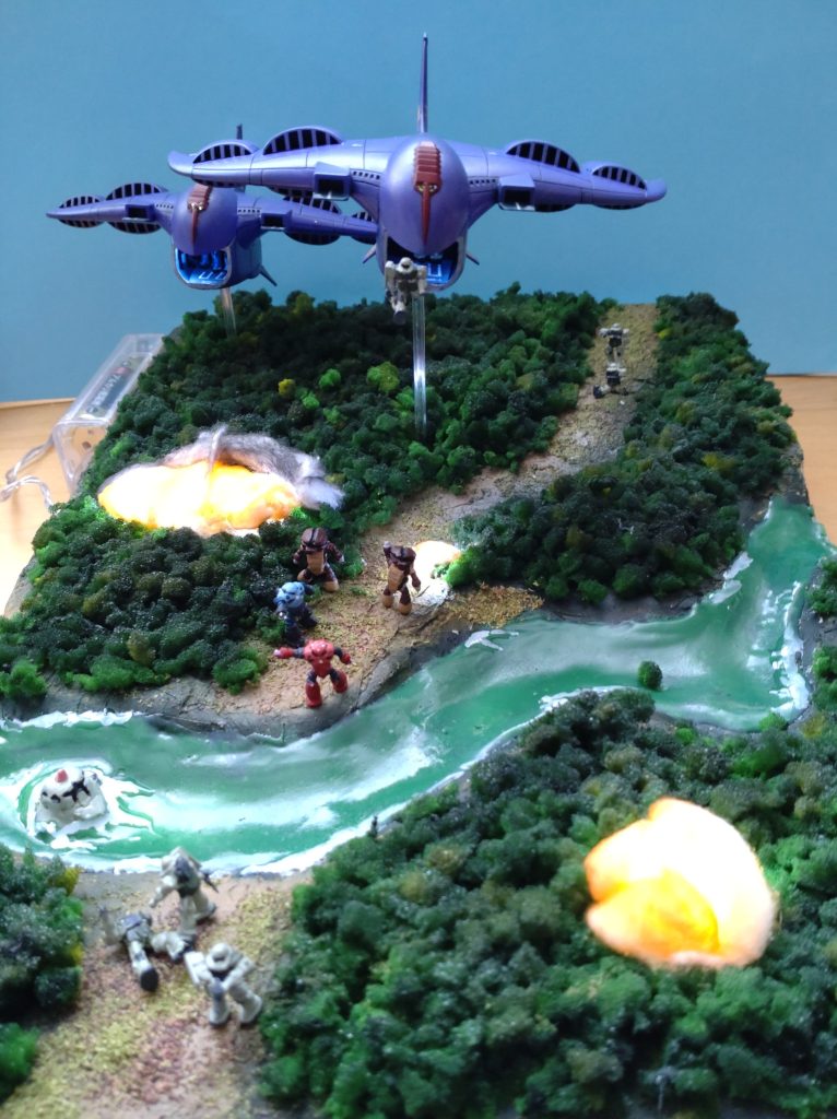 以下、おじさんの思い出話です。読み飛ばして下さい。数十年前の中学3年の時、夏で部活が終わってしまい、何もやる事が無く(受験勉強しろ)、あまりにも暇だったので(受験勉強しろ)、ガンプラ作りにのめり込みました(受験勉強しろ)。お小遣いで、旧キットを買っては、一寸だけいじって筆塗りをする日々(受験勉強しろ)でした。そんな時、田舎の百貨店で、「プラモデルコンテスト」があって、友人と一緒に応募したのがこの原型となるものでした。ガウは1機だけでしたが、前面開口させて、麦球(LEDは当時無かったなぁ)で格納庫を照らして、小さなMS達を入れたり、降下させたり、電源はガウを支える太い棒を這わして、外付けの単3電池に繋いでました。ジオラマは紙粘土に絵の具で色を付けて、粉粉を振っただけでした。百貨店に作品を持ち込んで、飾られている自分の作品が見られてるのが、何とも言えない喜びでした。数週間経って、母親から「百貨店から電話だよ」と言われて出ると、一般部門で3位入賞、商品券5,000円頂きました。高校に入って部活が始まり、サッカーやギターや麻雀やらで、プラモ作成とは縁遠くなりましたが、この時の原風景が、数十年ぶりにガンプラに出戻って、GUNSTA様で皆様の作品を見たり、自分の作品を見て頂ける喜びなんだと思います。長文失礼しました。ありがとうございます。