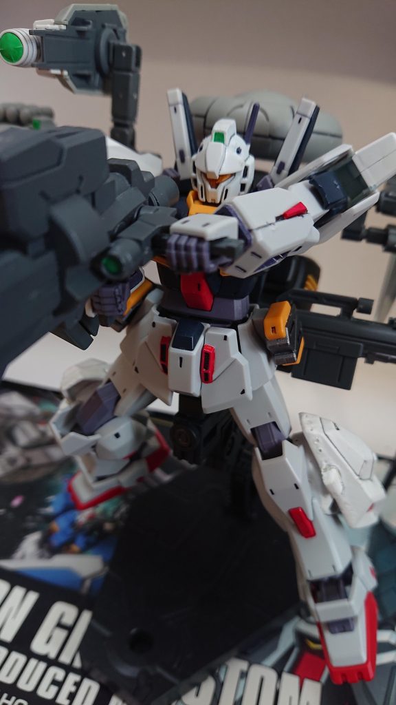 解説文③:エシュロン電子戦システム重装型第2仕様について②このオプションの追加火器について語る。まずレールガンはガンダムTR-6インレやネオ・ジオングなどのIフィールド搭載大型機を撃破するために作られた武装であり、様々な弾種も運用可能だ。また、マウントしたままの発射にも対応している。元々はRGZ-91Dの装備であったが流用された。ウィンチ・キャノンはガンダムTR-1系の発展型であり、出力などの改良が施されておりその出力は14MWとなっている。この装備は714部隊のMS戦隊司令となるエイレン・ユーリの考案であり、宇宙戦闘時の偵察ポッドやインコム的な使用に適するうえ高火力と説明された。そのためもあるのか、射出時の隠匿性向上のために黒く塗装されている。本装備はそれら大重量による弊害を出来る限り打ち消すため、大出力のベクタードブースターを接続しており機動性は担保どころか過剰とも言えるが、運動性の低下は否めない。解説文④へ続く