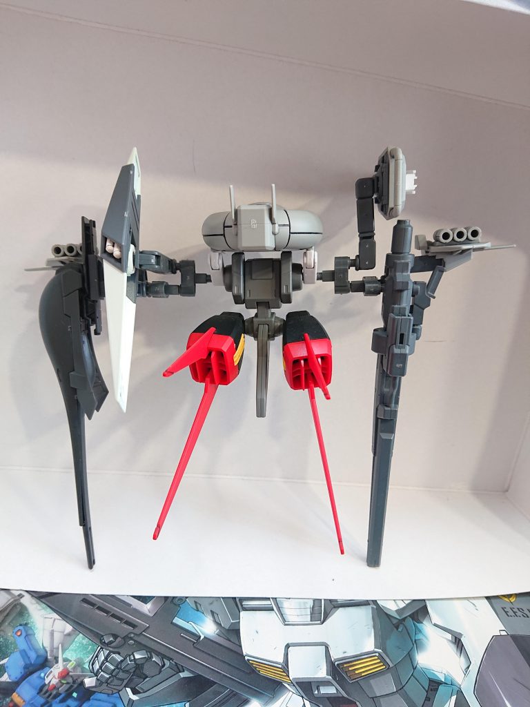 解説文②:エシュロン電子戦システム重装型第2仕様①本体重量:10.0t全備重量:22.5tジェネレーター出力:500kWスラスター総推力:80000kg装甲材質:ガンダリウム合金姿勢制御スラスター:4基エシュロン電子戦システム重装第2仕様は、エシュロン電子戦システムの重武装型の2番目の仕様であり、重武装Hの2番目の仕様のためH2と略される。まずエシュロン電子戦システムは既存のEWAC機が索敵をメインにしていた事に対し、ジャミングといった妨害機能も盛り込んでいる。しかし、そのためか高価かつ大重量となってしまった。また、EWAC機よりもレーダーの範囲は狭いがこれは本機が早期警戒機というより、部隊に随伴してジャミングなどを行い敵EWAC機からの探知を防いだりするといった目的があるためだ。仕様が示す通り複数の仕様が存在する。他の仕様としては重装第1仕様及び軽装第1仕様はデータ収集用のもの、軽装第2仕様は本装備と同じく正式採用型だ。軽装は略はLとなる。このオプションの電子戦機能に関して語る。レドームは広範囲レーダーだけでなく通信傍受機能が組み込まれている。シールドセンサーは一年戦争時の小型シールドの設計に長距離カメラとサブセンサーを組み合わせたもので、本機では前者としての使用を前提としている。また頭部の動きに追従して可動するようになっている。横に伸びるユニットは各種センサー類の塊であり、サーモグラフィ等の特殊センサー、外側に延びてるフィン状のパーツがECM、ECCMの発信装置で、肩部のマルチランチャーには通信妨害用の自立ドローンやジャミング弾又は電子パルス弾、その他弾頭が装備される。解説文③へ続く