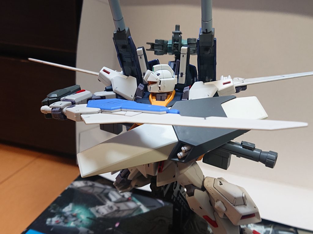 解説文③:MVS MVSの機能の詳細を話す。まずMVSは小型のサブジェネレーターを搭載しており、そこからも電力供給を受けるため機体のジェネレーターへの負担がかかる事は少ない。振動機能は、MVSの刃部分を振動させる事で敵機を切り裂くというものであり、これも対Iフィールド搭載機を意識した装備だ。ビーム・ブレイドについてはリーチに優れ、また両刃であるため敵の意表を突いた攻撃をできる。また、高出力ビーム・ブレイドを発振する事も可能である。これは機体のジェネレーター、BWSのジェネレーター、MVSのサブ・ジェネレーターを直結し高威力のビーム刃を発振する機能だ。欠点はサブ・ジェネレーターのエネルギーがビーム発振器の使用に限定され振動機能が使えない事や、何らかの原因でMVSが過熱するとMVSのサブ・ジェネレーターが破損する事、発振時間は3分であり終了後は1分程MVSのサブ・ジェネレーターの冷却を行う必要があり、その時間はMVSの全機能が使えない事が挙げられる。片刃に限定して発振する事も可能で、その場合は時間の問題は半減される。ビーム・ガンはビーム・ブレイドの発振器より発射される。出力は2MWで収束率も低いため牽制用の意味合いが強い。上の写真はをガザDをシールドごと切り裂く直前のものだ。解説文④へ続く