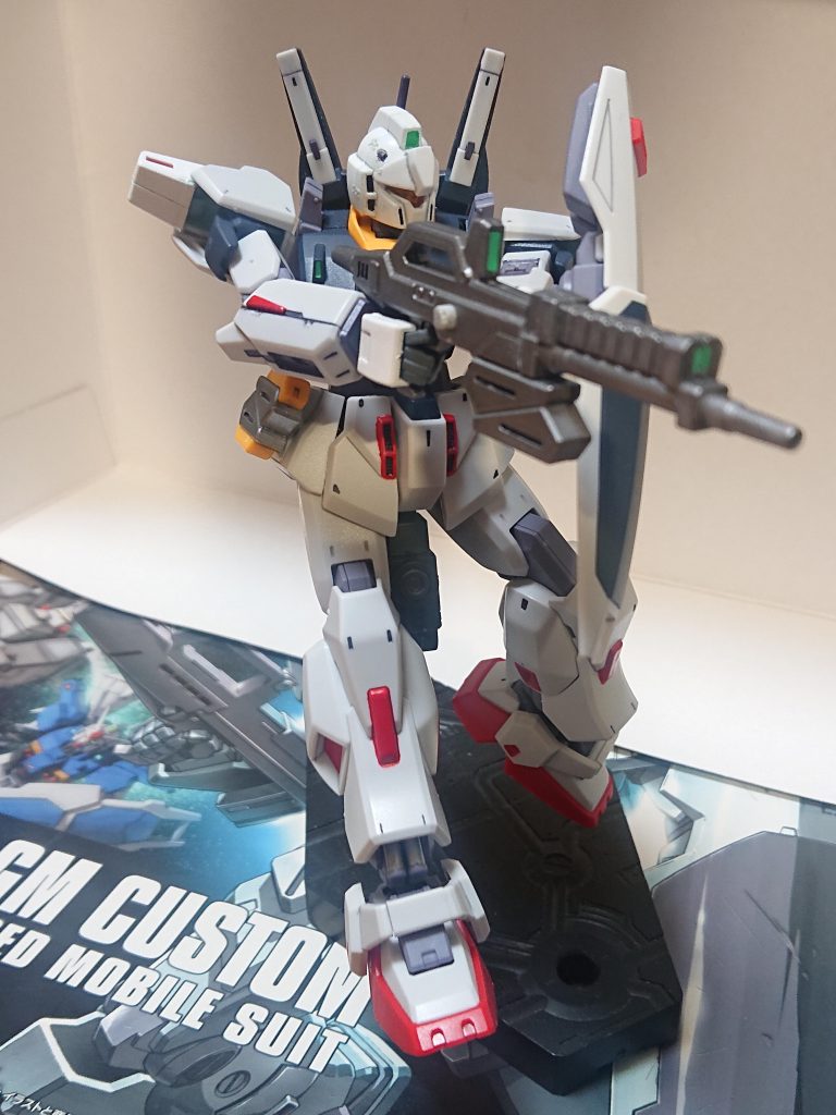 設定文③本機の武装について。固定武装に60㎜バルカン砲2門、ビーム・サーベル(出力0.45MW)2基がある。主な携行武装としてはビーム・ライフルやシールド(ヌーベル・ジムⅢと同型)、ハイパー・バズーカ後期型をブロック1の多くは用いていたが、ブロック1の一部よりAE社からの提供でガンダムTR-1ヘイズル系の装備するショートバレルのXBR-M84aビーム・ライフルを基に、ゼータガンダム系の長銃身ビーム・ライフルの設計を組み合わせたビーム・アサルト・ライフルが装備された。これは基のライフルの連射性に長射程や高精度といった要素が付与されたものであり、性能としては出力は通常出力で2.8MW、高出力モードで7MWほど、弾数は通常出力で20発、高出力モードで7発だ。ブロック3以後はジェガン用のビーム・ライフルやシールド、バズーカも装備され、ブロック4からはさらなる武装やオプション装備が運用される事となる。設定文④へ続く