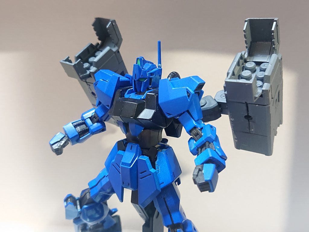 解説文②：本機の設計本機は百式のムーバブル・フレームや外装を基にしているも、装備試験機という事で内装品や装甲材はワンランク下のものが用いられている。そしてバインダーの代わりにはメガ粒子砲やミサイル・ランチャー、ロング・シールド・ブースターといったオプションが装着される事を前提に、周辺のエネルギー経路が多少見直されている。イデシステムはオミットされた代わりにオプション装着時のバランサー制御の補助装置が内蔵された。また、原型機の耐ビーム・コーティングも不用として青く塗装されたことから、原型機のさらに原型機の名前と組み合わせてデルタヴォーテクスと命名された。本機の性能は原型機よりワンランク下だが、リック・ディアスよりは高い性能であった。上の写真ではミサイル・ランチャー2基を装備している。解説文③へ続く