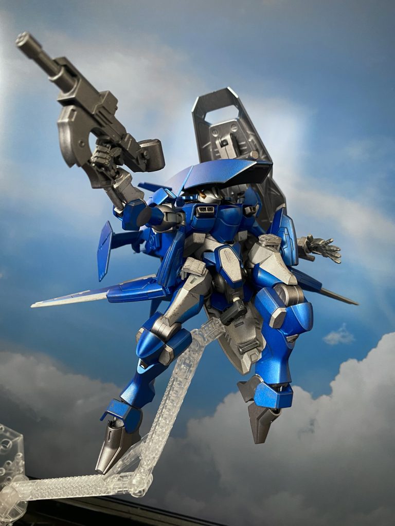 「通常」空中機動形態 脚部腿に装着されたウイングユニットの展開により空中機動時の高い安定性を持つ。それにより、飛行中であっても精密な射撃を可能としている。試作ショートバレルビームバルカン ザウォートのビームガンをベースに、射撃性能、携帯性を維持したまま火力向上されたライフル。回転式銃身を持つが、ガトリングガンのように銃身が回転してから発射されるのではなく、ビーム発射後に銃身が回転、その隣の銃身から発射される方式になっている。連射から精密射撃まで様々な射撃に対応している。マガジンは多弾倉タイプを使用。なお、無骨な形状をしているが、「試作」段階の為であり、本採用の際は機関部と銃身部を覆うようにカウルパーツが被せられる。