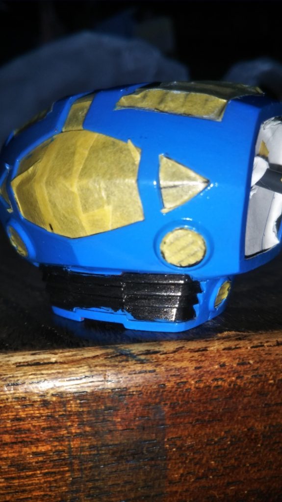 　マスキングです。　先ほども述べましたが、上半身のスカイブルーはツヤ消しスプレーを吹いてあるので、その前にマスキングテープやいらない紙でモノアイカバーの透明パーツや肩関節、ブーメランカッター射出部の黒鉄色を保護してやりました。