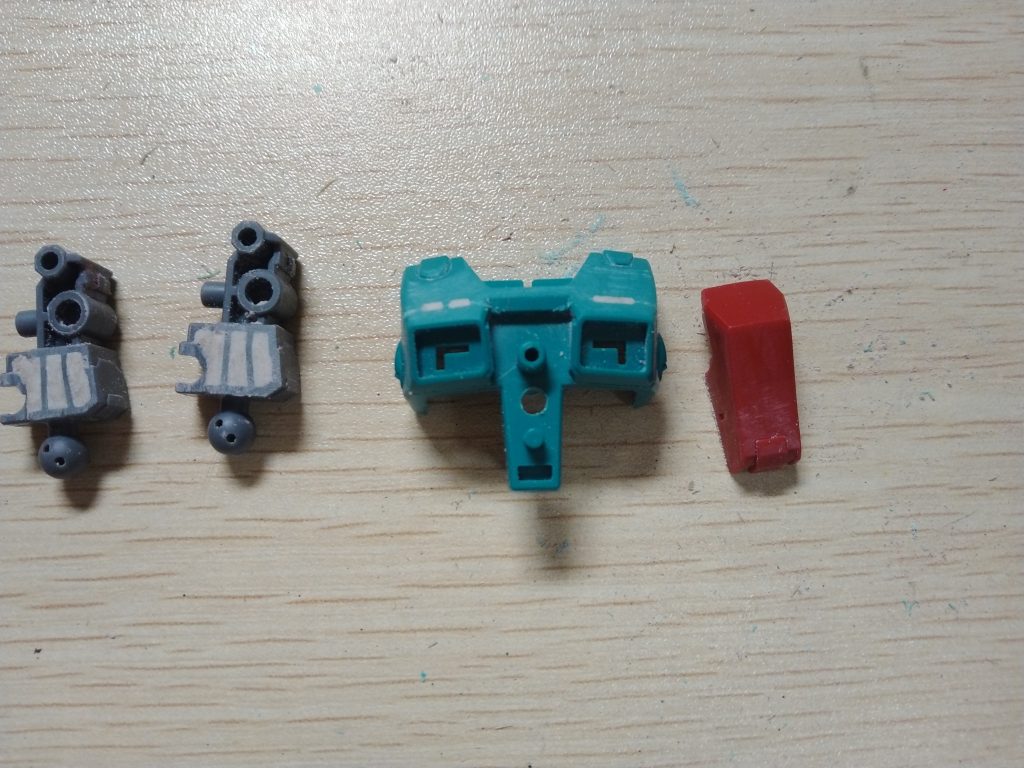 胸部ダクト上の凹みをパテで埋めてからスジ掘りし(中央緑色のパーツ)、胸部中央のハッジ部パーツを平らにし(左の赤いパーツ)、