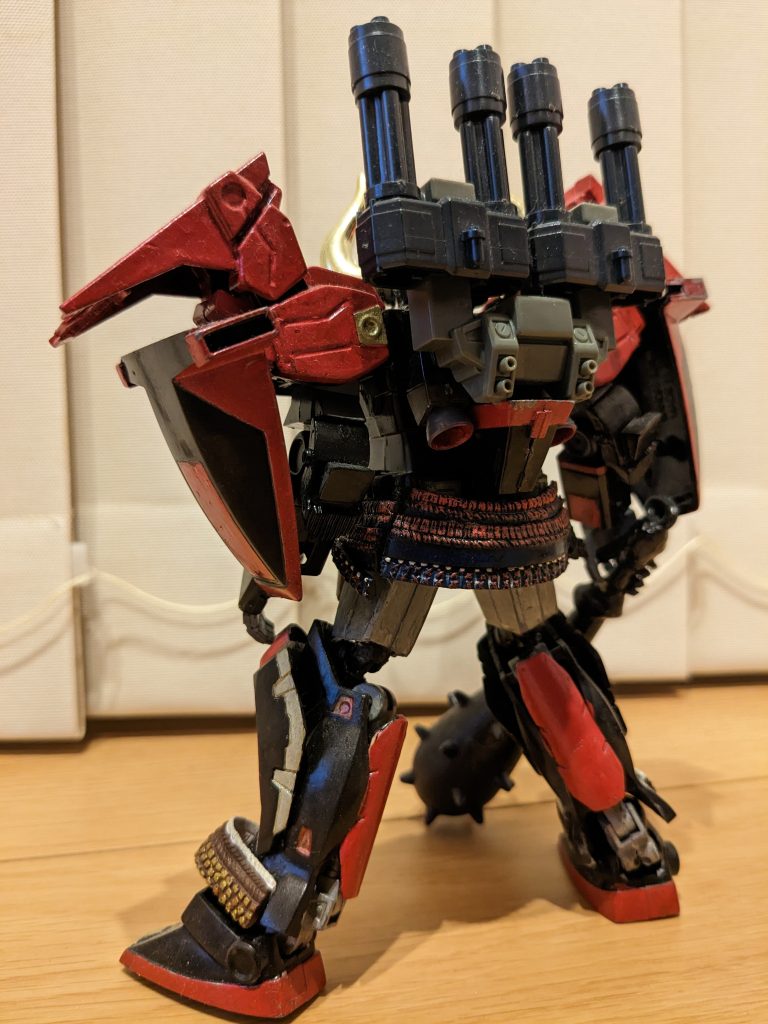 バックショット。関節は少し手を加えて、開脚と接地感が多少良くなっているかと。スネや腰の帷子っぽいのは、武将兜のガチャから源義経の帷子部分。武器の金棒はワンピースのものです。で、リメイクで鉄機武者斎胡というのが当時あったため、それっぽさも織り交ぜたいと思い、武者ヘビーアームズのバックパックをダブルガトリングごと装着。それっぽくなったのではないかな〜と思います。