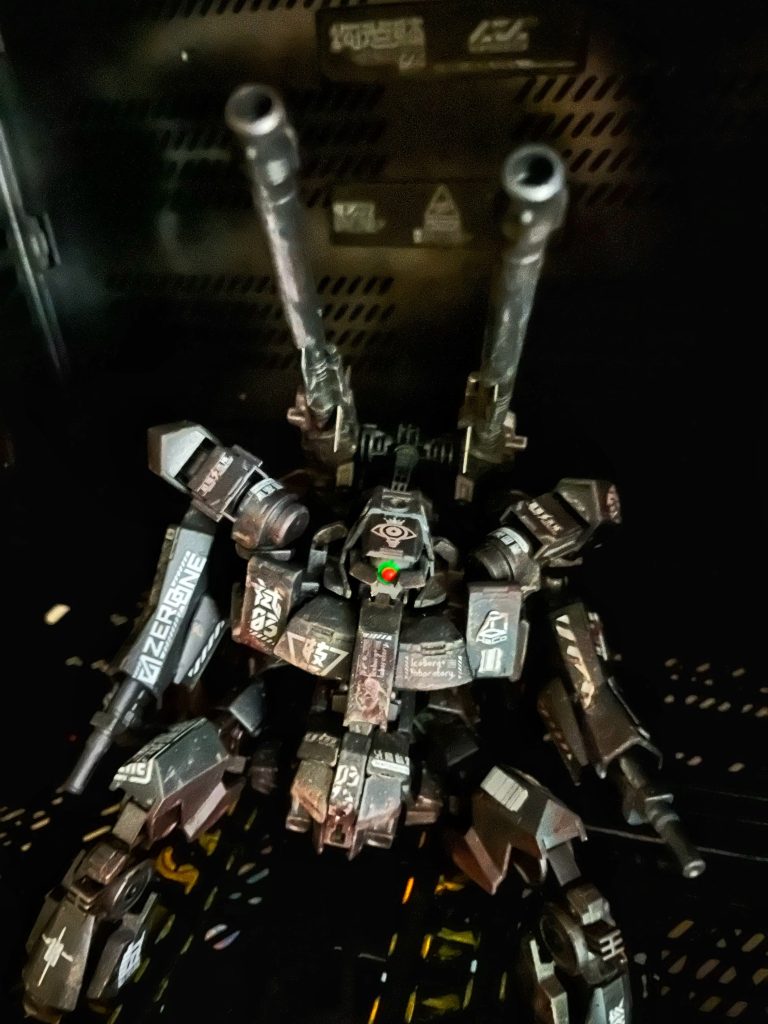 [ヒケンタイ　0720バン　キドウ]脳内に無機質なマイコ音声が流れる。ーーここはどこだ....最後に覚えている光景は...手術台...?ーー[0720バン　キドウシテクダサイ　サクセンクイキマデ　300ビョウ]ワタシは意識を感覚を[立ち上げる]ーーーーッ！身体中に激痛が走るッ！？身体！？ワタシの身体は何処だ！？無いッ！無いッ!ワタシの身体は!!!何故[脚が四本]有るのだ!![キドウ　シッパイ　0720バン シャットダウン　ノチ　サイキドウ]けたたましい警告音と共にワタシの意識がまた遠のきかけるーーーまたーーー？いや、コレをワタシは何度か経験しているーーー？そうか、そういう事か。思い出した。クローン培養の脳では無く「私」の脳を使ったのか！上の奴ら、やりやがったんだ！事情を理解したワタシはシステムのコントロールも理解した。AIからの情報が流れてくるのが解る。何度か起動に失敗したようだが今回はーーーいけるーーー[シャットダウン　ガ　ヒケツサレマシタ　0720バン キドウ　セイコウ　サクセンガイヨウ　ヲ　カクニンシテクダサイ]膨らむ負債に手を焼いた我が社上層部と、融資してくれた企業達が痺れを切らして...私自身を拉致なりなんなりしてMSに取り入れたのだろう。コントロールの主導を握ってからは苦痛もいくらか和らいできた。人機一体とはこの様な気分なのか。案外悪くは無い。ワタシ自身が律するならば、パーメットは必要無いだろう。これならば永続的に闘えるッ！[0720バン　コレヨリ　サクセンヲ　ツウタツスル].....子供が興味を無くした玩具を放り投げる様に、船体に吊られたワタシの身体がアンカーから切り離され無造作に投げ出される。ロマン主義の名残である四本脚が難無く瓦礫の地面を受け止めた。主力部隊が暴徒を掃討したので残存勢力を刈り尽くして来いとの命令だ。期間は未定、作戦区域外に出る事は許されない。が、こいつのーーーワタシの実力ヲ魅せル時だ...殺っテヤる.....私がワタシを受け入レた瞬間、私ノ意識はワタシに飲マれ、消えテイッタ...此処が何処ナのか...ワタシにハもう興味ガ無イ....敵は...敵h a ド　こだ....出撃か　ra dぉれだけ　   　時kaんガ経ッ　t...a.... nぁん　年...keい過...