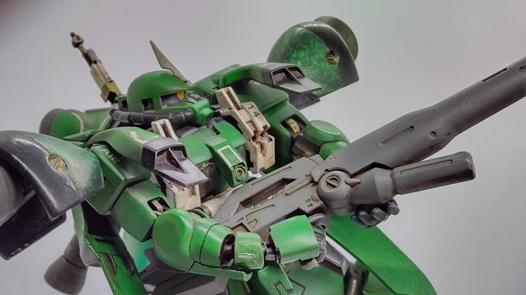 機体コンセプトはザク2S型やガーベラテトラ同様「強襲性の高い汎用機」という位置づけ。肩にはガーベラテトラの肩部大型バーニアとショルダーアーマー増設が、脚部にはバーニアが増設されており高い機動性を誇ります。機体正面には装甲が増設されており、継戦能力が向上されています。肩部大型バーニア表面はラップ塗装されていますが、これは「シェルユニット(水星の魔女)に似た演算ユニットにもなっており機体のパフォーマンスに応じて緑に強く発光する」という設定にしました。……このカラーデザイン自体がFC岐阜の2022年・2023年ホームユニフォーム」を意識したものですが、このユニフォームの独特のモールドをこの肩バーニアで表現したつもりです。武装はビームマシンガン、ザクマシンガン、ザクバズーカ、ビームサーベルなど。