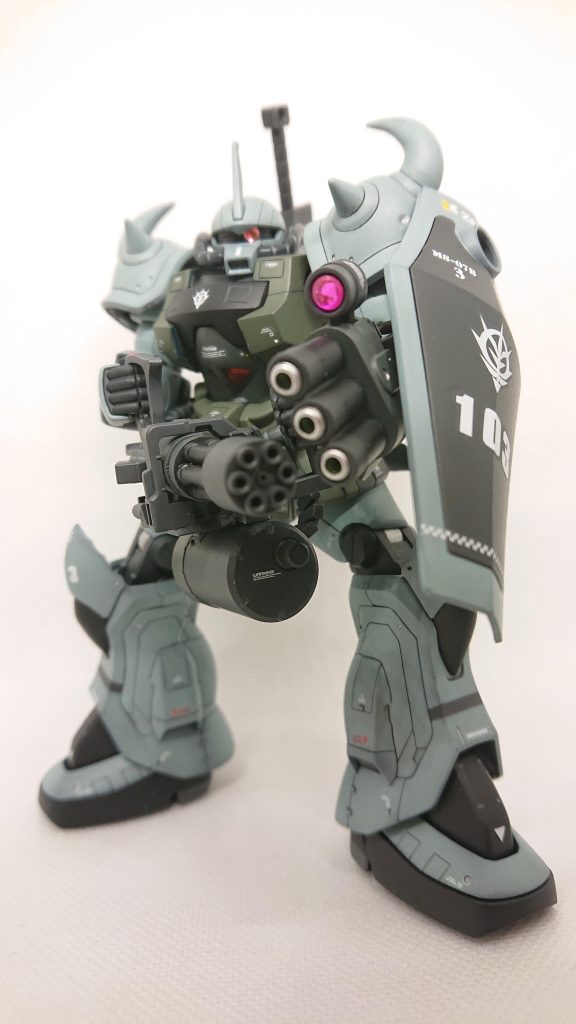 前方より武器を携えて。今作は前2作と並行して作製していました。前作を塗装した段階で機体自体はほぼ完成していたのですが、携行武器がなかなか上手くいかず…。ここまででグフカスタムの携行武器といえばガトリングシールドだろと聞こえてきそうですが、武器なのか、防具なのか、実体弾がまだまだ主流の一年戦争において盾に爆発物を付属させることにどうしても違和感があり、何とかしたいと以前より考えていました。そんな時、私のフォローしているあるお二人の作製されたグフカスタムを見て、ガトリングシールドを何とか右手持ちに変えようと試行錯誤した結果この型になりました。右手持ちというか、両手持ちになったので、シールドをより大型なリバイブグフの物に換装しました。射撃しながら防御もできそうです。何より楯の丸窓を活用できそうです。