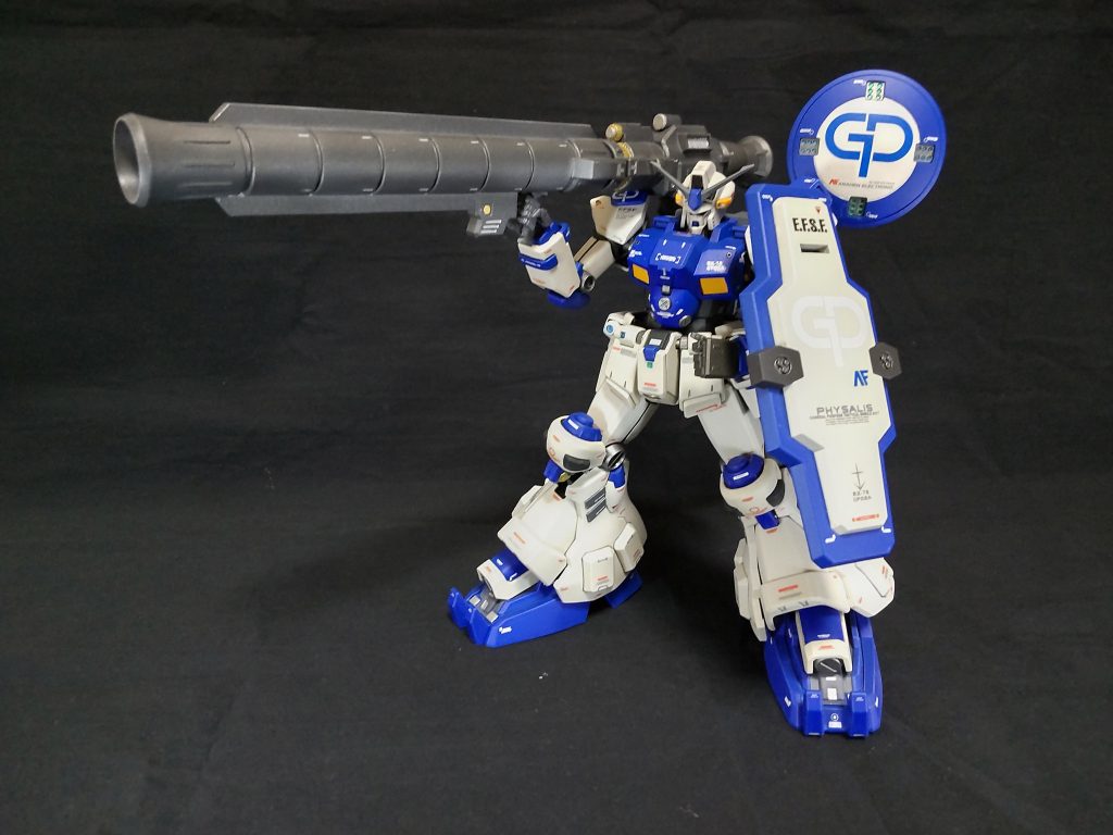 アトミックバズーカの運用試験シュミレーションの結果、現状では想定している核弾頭出力の半分も発揮できないことが判明。下記課題の解決が必要となった。アトミックバズーカ発射時の機体保護のための冷却方法の検討重装甲化に伴う機動力の確保アトミックバズーカの運搬方法と弾頭の搭載方法上記課題を解決するため、後に開発されたのが大型ラジエーターシールドとフレキシブルスラスターバインダーである。また、アトミックバズーカは分割できるように改修し、分割したバレルをシールドに収納、発射時にシールドからバレルを取り出し、基部を連結、同時にバックパックから基部に弾頭が装填される搭載方法が開発された。