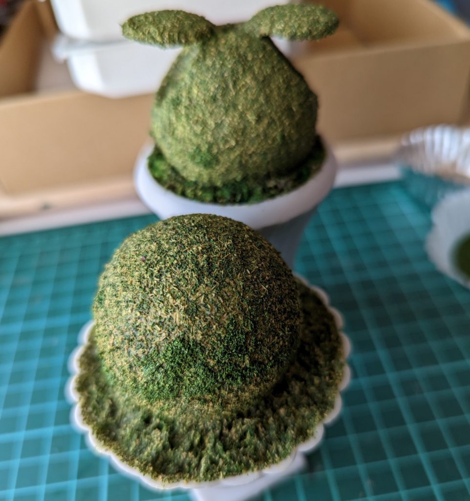 プランターの底に自作のレンガパーツを置いてその上にウッドチップや細かい木材、グリーンモスなどで中を埋め、ハロにはグリーン系のパウダーや細かいモスなどを配合したものを張り付けました。それを土台のプランターに固定し、周りを更に埋めていきます。