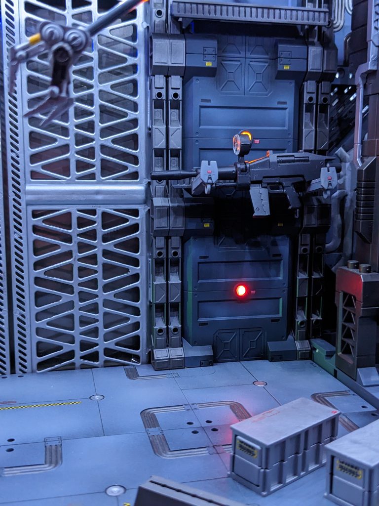 シャッターはダイソーのアルティメットコンテナを加工して使用。奥の銀の板は、なんとお煎餅が入っていた金属製箱のフタです。LEDの光を反射してくれます。壁のアームは武器をホールドできます。