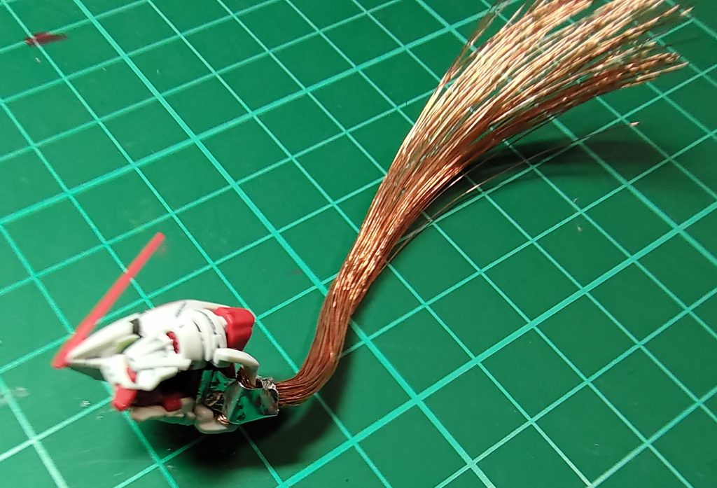 改造と言いつつ、プラモ本体は全くと言っていいほど弄っていません。後頭部の下にあるパーツに、廃棄予定だった電化製品のケーブルから採取した銅線を通してアルミテープで留め、ニッパーで毛先を整えました。