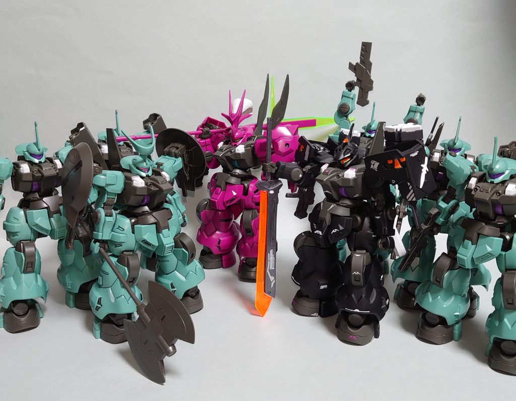 こんな感じで実際にジェターク寮に混ざっても違和感ない感じに作ってみました。以下、いつもの機体とパイロット解説です。【ディランザ（ムラクモ専用機）】ムラクモ専用に調整されたディランザ。カラーリングは黒と橙。両肩にマルチランチャー、背部に専用ヒートソード「トツカ」を装備する。両肩のマルチランチャーにはディランザ・ソルに搭載されるクラスターミサイルの他、スモークやチャフ、対ビーム拡散弾などが装填可能であり、状況に応じて使い分けて敵機をかく乱させつつ接近し、トツカで仕留めるのを基本戦術とする。彼の戦闘スタイルに合わせて、脚部ホバーと両腕部の出力が高めに調整されている他、稼働時間延長の為、背部にはプロペラントタンクが二基増設されている。また、マルチランチャーやスモークの使用に伴い、肩部と頭部のセンサー類が強化されている。コックピットブロックには意志拡張AI「SUSANO-O」が搭載されており、戦闘データの学習を行っている。機体の制御は基本的にパイロットと通常のOSで行うが、任意でSUSANO-Oを使用することもできる。一応はオートパイロットモードでの運用も可能だが、本機はあくまでもAIの学習を目的とした機体であるため、パイロットありきでの運用が前提となる。その機体特性からジェターク寮の機体の中では珍しく集団戦での運用も得意とした機体となっており、集団戦の際にはムラクモと共に真っ先に僚機として駆り出される。そういった意味でもムラクモを象徴する機体と言える。プラント・クエタ事件後、SUSANO-Oの最前線でのデータ収集の為、機体はジェターク社に戻されることになる。その後、トツカは専用武器を欲しがっていた同ジェターク寮のフェルシー・ロロへと譲渡される形で学園に残された。