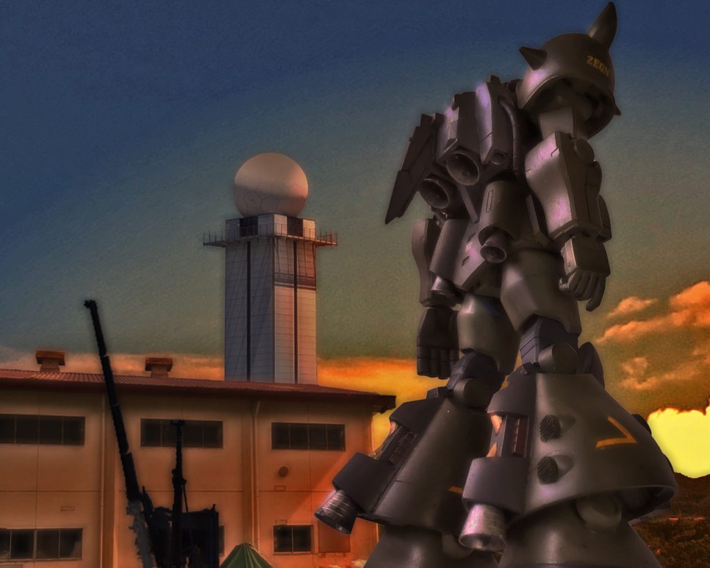 「随分珍しい物がありますね」エイプは夕焼けに照らされる1機のMSを見上げた。「ああ、あれはこの一帯を纏める基地司令部から送られてきた試作MSですよ。まあ最も失敗作らしいですが」「MS-07H」「ご存知なんですか?」「まあ技術屋ですから。それにうちでも06や07はライセンス生産してますから多少の事は知ってますよ」「何でも飛ぶらしいですが、従来のザクやグフとは違い過ぎて、ここのメカニック達ではお手上げなんです。何回か動かしたんですが飛ぶどころか移動時に安定すらしないので、ここじゃ只の飾りです」「07Hは構造的にかなり無理がありますからね。よろしければ我々が見ましょうか?」「えっ?」「あの機体の問題は飛ばすのに強引に出力と推進力を上げているのと姿勢制御のOSなんですよ」「はぁ」「我々が運んでいる新型の09は飛ぶのとは違いますが、07H同様地上から離れるという点は同じです。自慢じゃないですが動力や推進周りに置いてはジオニックより先を行ってますし、09のOSを用いれば化けるかも知れませんよ」「そりゃ助かります。連邦軍がこの基地に進軍している情報もあるので、今は少しでも戦力が必要なんです」「なぁに、護衛の代金と言っては何ですが半分は技術屋の好奇心ってやつです。部品は三連星に届けるので渡せませんが、OSは09のをコピーして渡せます。あとここの資機材と人員をお借り出来ればやってみせましょう」「お願いします。人手は限られてますので今夜は互いに徹夜ですな」