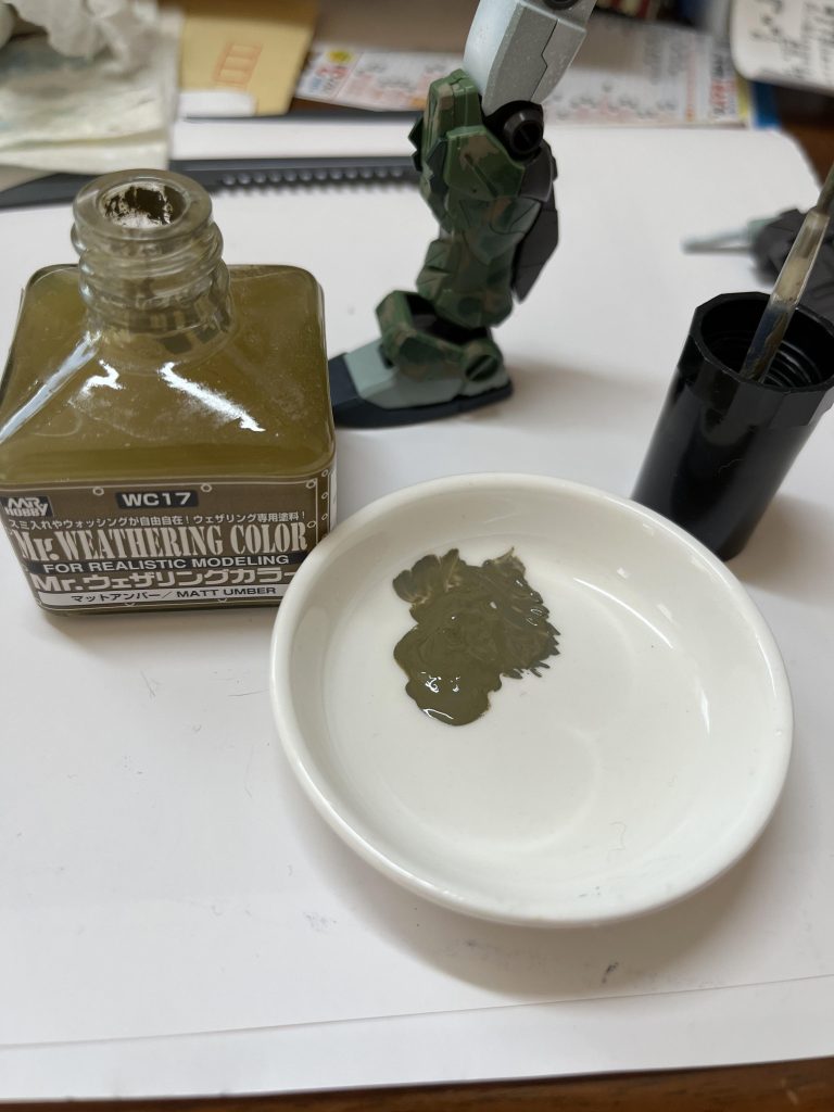 迷彩使用色は、Mr.ウェザリングカラー フィルタリキッド:フェイスグリーンMr.ウェザリングカラー:マットアンバーMr.ウェザリングカラー:グランドブラウンです。撹拌する前の、下に沈殿した泥状のをすくい、メインのフェイスグリーンは文房具屋さんで買ったフィルバード筆0号でペタペタと、心の赴くままに…今回薄め液は使わず、上澄みで適度に塗り易くして描きました。2色目のマットアンバーはキャップに付けた接着剤用筆で、同様に泥を薄めながら直接ペタペタ…3色目のグランドブラウンは色が濃いので軽く混ぜ、キャップに付けた筆で水分をワイプで十分吸ってから、ポイントとして入れました。成形色のグリーンも残してあるのでボディーは4色迷彩。シールドは、ガンマカ・ニューホワイトで塗らなかった薄みどりの成形色含めて5色迷彩になりました。ホワイトで塗った部分はマルチグレーやグランドブラウンで軽めにウェザリング。最後は水性トップコートつや消し仕上げです。ウェザリングカラーはその場の思いつきでメインとなる迷彩色として使いましたが、乾きが遅いぶん、修正も容易なので思いきってやれました。ウェザリングやフィルタリング以外にも使っていこうと思います(^^) 迷彩塗装、めちゃくちゃ楽しかったー❗️ずっと描いてたかったです。最後までご覧いただきありがとうございます。
