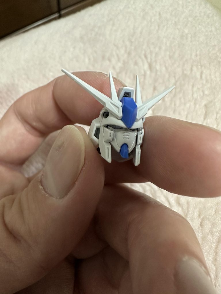 実は、ヘルメットパーツに多少加工しています。個体差かもですが、ヘルメットパーツが多少狭くデフォルトのフェイスパーツの位置ではちょっと馬面だったので、ヘルメットの合わせにプラ板挟んで少しだけ幅を広げて、フェイスの差し込み上端をちょっと削ってフェイスがデュアルアイのパーツにしっかり密着するよう調整しました。