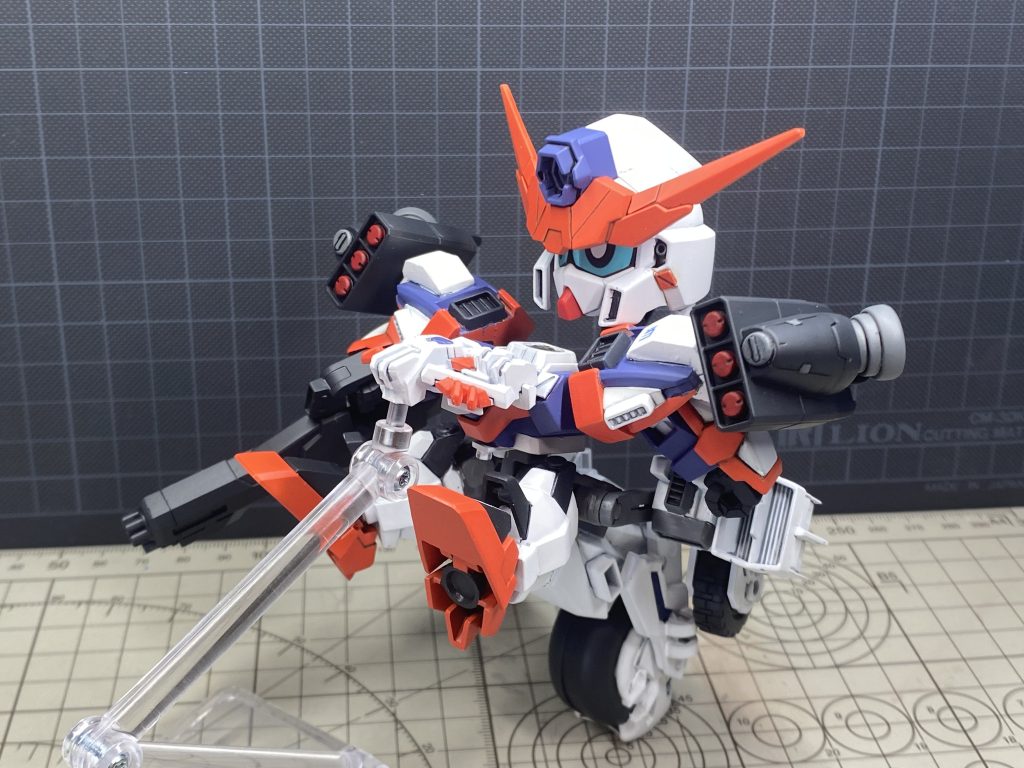 変形途中。頭がフレームを介して背中に移動。下半身がフレームごと上下前後が反転して足が後ろ、バックパックが前に移動します。腰アームから生えている後輪は下半身フレームの変形に干渉されず元の位置をキープします。前かけは胸の前に移動、腕は90°後ろに向きます。