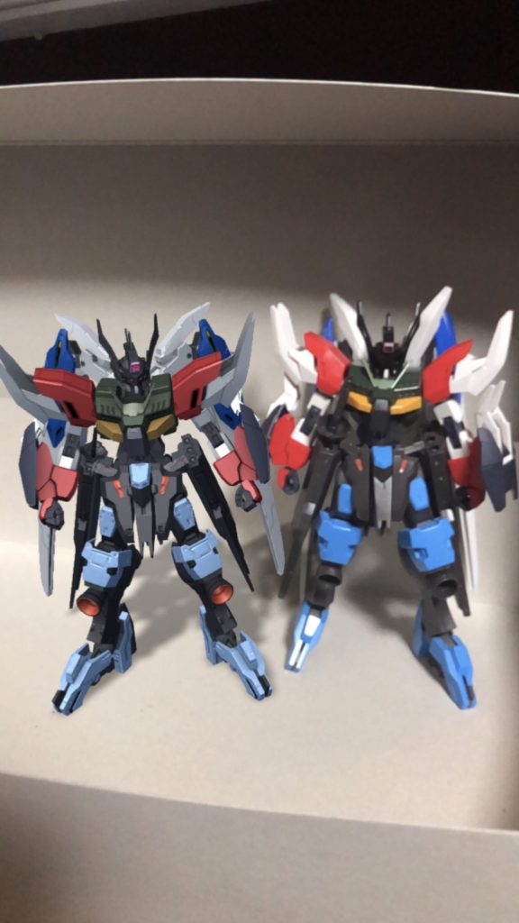 作成した機体を実際にガンプラとして組み合わせてアプリ内のAR撮影でデフォルトカラーの機体と一緒に撮ってみました。そのままだと胴体に脚部とバックパックが接続できなかったので、それぞれカスタマイズキャンペーンやバルバタウロスのパーツを使って接続しました