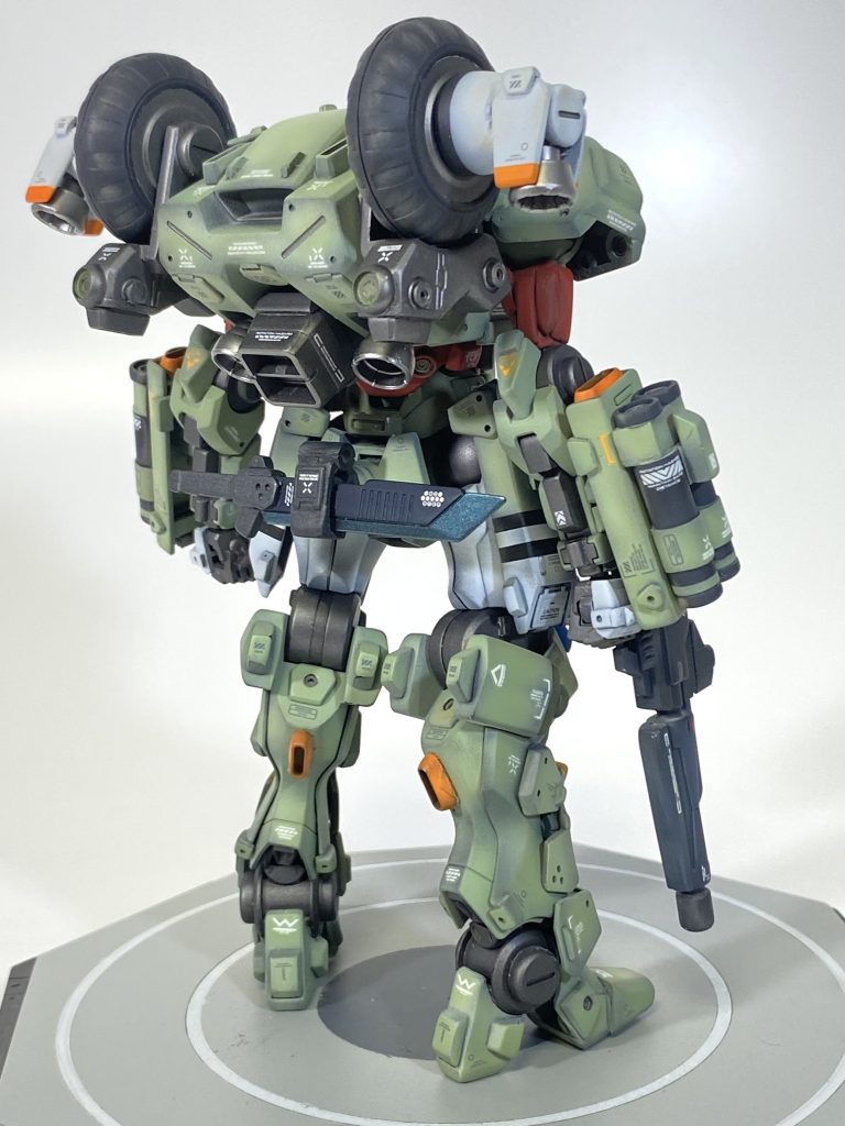 背面から 目を引く車輪はタイヤではなく、某リアクター技術で開発されたアンチグラビティホイール。反重力による機体重量の大幅低減とスラスターにより低高度の飛行が可能。 またリアクター技術と組み合わされたラミネート装甲により超高硬度装甲を実現している。