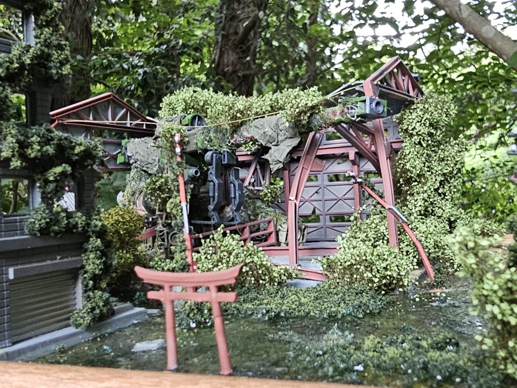 電柱や看板に植物をつけることで自然の力強さを強調しました。また鉄筋はデミトレーナーが倒れたさいの重みでひしゃげてデミトレーナーの下敷きにする配置をとっています。