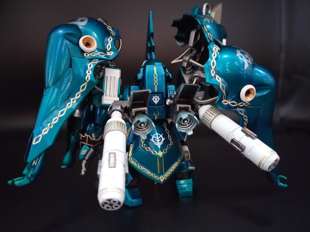 （ボディ色は、以前にも試した、レッドゴールド＋クリアブルーでドズルザビチックな色合い・・になってますよね？！とドズルザビオマージュでエングレービングをエレガントカットシールで再現。これでちょっとはドズル味が出たハズ）ベース機は、当時ネオジオンの次世代フラッグシップ機として開発を進めていたNZ-000クインマンサとそのダウンサイジング機のNZ-666　クシャトリヤとなる。上記2機は共に開発途上にあったが、その基本フレーム及び技術はほぼ完成しており、その技術を応用し、開発が進められた。