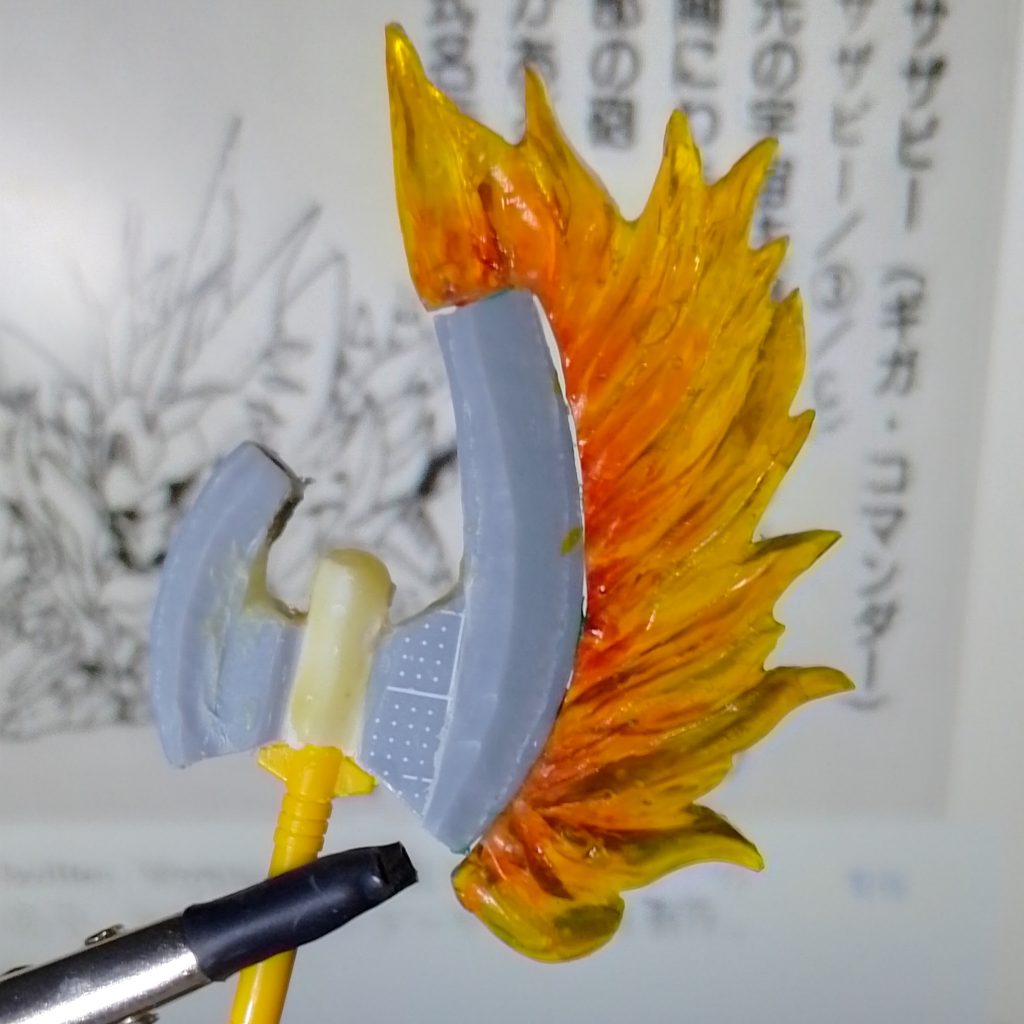 ビームアックス武器の設定画が全くないのでコルナシ版の写真を参考に作るしかありません。 斧はEXSDサザビーのビームサーベルをそのまま改造し、側面をフィルムで拡大。斧の刃はダイソーの樹脂粘土で形を作り、UVレジンで透明パーツに転写しました。 斧刃の炎はスラグ染めで透明イエロー+透明オレンジで塗装。