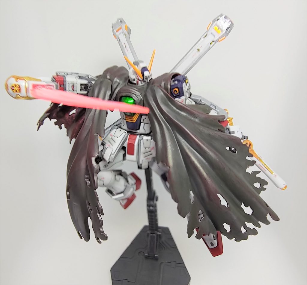 ABCマントはX1フルクロスを意識して、裏地にクリヤーレッドでラップ塗装し、リンゴ飴状態になったところでつや消しを拭きました(マットキャンディ塗装って言うんですね)。シックな感じになったと思います。表側はリアルタッチマーカーのブルーで全体をぼかして陰影を付け、リアルタッチマーカーのレッドを含ませたスポンジで擦りました。戦闘による表面の損耗が重なり赤い裏地が透けてきてるような感じを目指したつもりです。さらにウェザリングマスターのライトガンメタルを表全体にまぶしました。ビームザンバーのナックルガードにクロスボーンバンガードのエンブレムデカールを貼ったのは地味に好きなポイントです。