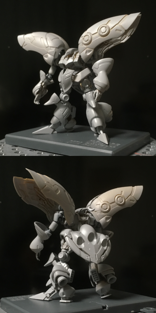 (初サフ後)塗装工程いよいよ塗装工程に入ります。百均のタレビンの先端を少しカットして、ガンマカの替え芯を差し込めば、調色した塗料をガンマカエアブラシで吹けるという裏技があるのをネットで見つけ、実際にそれをテスト。塗料は匂いもなく、乾燥前は水で落とせ、乾燥後は塗膜が強く、別の種類の塗料の上塗りできるというアクリジョンを採用。いざやってみると…全然問題なく使えるじゃないですか!これでガンマカの色に縛られずにエアブラシ塗装ができる!素晴らしい!フレーム部分から塗装開始。2体目の時はガンマカのメタリックブラックで塗ったのですが、ちょっと濃すぎてせっかくの細かいモールドが見えにくくなったので、アクリジョンの黒鉄色にホワイトを混ぜて使用。なかなかいい感じで塗れました。さらにシルバーでドライブラシを。うん、いいぞいいぞ。悪夢のはじまりこの方式がいけると分かったので、白・赤・紫部分の本格的な塗装に入ります。テストの段階でホワイトも吹いてみたのですが、つやありで隠ぺい力も低く感じたので、サフの効果もあるというベースホワイトを使うことに。が、なんか様子がおかしい。ちゃんと塗料が出ない。粒子も荒い感じ。ちゃんと薄め液も入れたのになぜだ?替え芯の位置やにじませる塗料の量、吹きつける距離とか角度をいろいろ試行錯誤してると、ちょっといい感じで吹けたと思ったら、次のパーツではまた吹けなくなる、と安定しない。そのうちエア缶が冷たくなって使用不能に。どうなってんだこれ?原因は定かではないものの、エア缶待ちでは作業が滞るので追加購入して複数同時使用体制に。替え芯とタレビンも新しくし、薄め液を若干多めにして再トライ。イマイチいい感じで吹けないものの、とりあえず何度か重ね塗りしているうちに下地が見えなくはなってきたので、とにかく全パーツの塗装を何とか終える。しかし…白くはなったものの、何これ漆喰?というような表面状態に。そして苦労して彫ったスジボリもなんか埋まってる。ダメだ終わった。一番きれいに塗りたい白がこんなことになるとは。その絶望感たるや。いやあきらめるのはまだ早い!…と、1000番でやすりがけをしてみる。当然エッジ部分などを中心に塗装が剥げて下地が見えるものの、とりあえずスベスベには戻った。埋まったスジボリも改めて彫りなおし、仮のスミ入れをしてみると、そこそこ復活できた。改めて塗装するしかないわけですが、もう一度やっても同じことになる可能性が高いでしょう。どうしよう?エアブラシ購入しょうがない。初心者用のエアブラシを購入して、普通にエアブラシ塗装しよう。というわけでMR.HOBBYのプロスプレーベーシックを急遽購入。これで白の塗装問題は解決だろうと、すぐ使用開始。粒子が荒くなる問題も解消されるはずだが、つや消しすぎると場合によってスミ入れがにじみかねないので、今回はベースホワイトに通常のホワイトを半々に混ぜて使用。使用感としては、いやガンマカエアブラシの時とは比べ物にならないほど塗料の消費が早くてびっくり。吹付の加減がわからず、たれてしまうほど吹いてしまい、このままじゃまたスジボリが埋まってしまうと混乱するも、アクリジョンは乾く前なら水で取れるということを思い出し、ウェットティッシュで塗料を拭きとったり、と一筋縄ではいかず。ただそこそこ滑らかな形で白を塗ることには成功。何とかリカバリーできそうだ。マスキング地獄予想外のトラブル続きで、この段階でもう締め切り1週間前。1週間余裕を持っておいてよかったとマスキング塗装に入る。MR.HOBBYの細切りと円形のマスキングテープを駆使しながら、赤線の部分を残してマスキング。あまりの数の多さに気が狂いそうに。そしてガンマカエアブラシで赤を吹き付け、マスキングテープをはがしてみると、あちこちはみ出たりにじんでたり。なんで…。再びの絶望感。エアブラシで白に塗りなおすことは簡単にできても、もう一度全部マスキングして再トライなんて無理だよ。とてもそんな気力残ってないよ。締め切り間近の悪戦苦闘何とか筆塗りではみだし部分をカバーできないかと面相筆で塗ってみる。修正はできたが、今度は筆塗り部分がムラになってる。どうすんだよこれ。また1000番でやすりがけを試みるがうまくムラは解消せず。下手にやって下地が見えてしまったら、また筆塗りでカバーしてムラができることになるので、あきらめる。クリアを吹き付けたら、多少目立たなくなったりはしないだろうかと試してみたものの、多少マシになったぐらいでムラは消えない。もうこれでよしとするしかない。バインダーの細かな塗り分けは後回しにして、先にスミ入れをと思うが腕や足を黒で入れたら途切れ部分ができてしまい再び掘り直し、再スミ入れということになってしまったので、バインダーはグレーで目立たない形でやってみることに。ここから彫り直しとか無理なので、現状できれいに入らないなら、バインダーのスミ入れは割愛することに。デカールはジオンのマーク3つだけ。ひざ横の円形部分にはメタルパーツをつけるべくスピンブレードで穴を深くしておいたのですが、案の定白い塗料が隅にたまっていて、再び平らにしたものの接着したらうまくはまらず、竹串で押し込んだら、今度はメタルパーツが歪んでしまうことに。ああ、何やってんだもう。いや、もともとキットのバーツから切り出した時点で一部欠けていたりしたし、ここは逆に丸モールドのディテールアップパーツに差し替えられてよかったと考えよう。ただ白く塗装する必要はあるじゃないか!締め切り前日の決断そんなこんなで気づくと締め切り前日。まだやらかし箇所の修正作業終わらず。これはもう状況的に、最初にイメージしていた完成形まで仕上げるのは無理です。撮影も原稿もまだできてませんし。いろいろ不満が残る部分はあるものの、やらかし個所の修正だけ済ませて、「これで一応完成」とするしかないと方針転換を決意。何度となくあきらめかけながら、ここまで来たのだから、もう応募しないという選択肢はない!そして…GUNSTAのアカウントを作成し(←ここでか!?)、投稿の仕様を確認しようと画面やヘルプのガイドをチェック。うん、なるほどなるほど、そういう風になってるのね。…と、あれ?コンテストタグの項目に「赤い機体」「青い機体」とあるのに「アーティファクトコン」がない。え?嫌な予感。でも締め切り18日までだったはずだよね?イベントの項目からアーティファクトコンの応募要項を確認。は? 14時まで!? 終日じゃないの!? もう締め切り過ぎてんのかい!終わった…アホすぎる。あまりにもアホすぎてもう笑うしかないよ…ここ何日かの睡眠時間を削っての悪戦苦闘は何だったんだ…思えば…遅くとも締め切り1週間前には投稿するつもりでいたので、最終日の終了時間なんて気にしてなかったんですね。それが思いがけないトラブルの連続でずるずる作業が延びていくうちに、勝手に日付が変わるまでと思いこんじゃってた、と。ハハハ…。というわけで間に合いませんでした。チャンチャン。 悪戦苦闘の結果はこちら