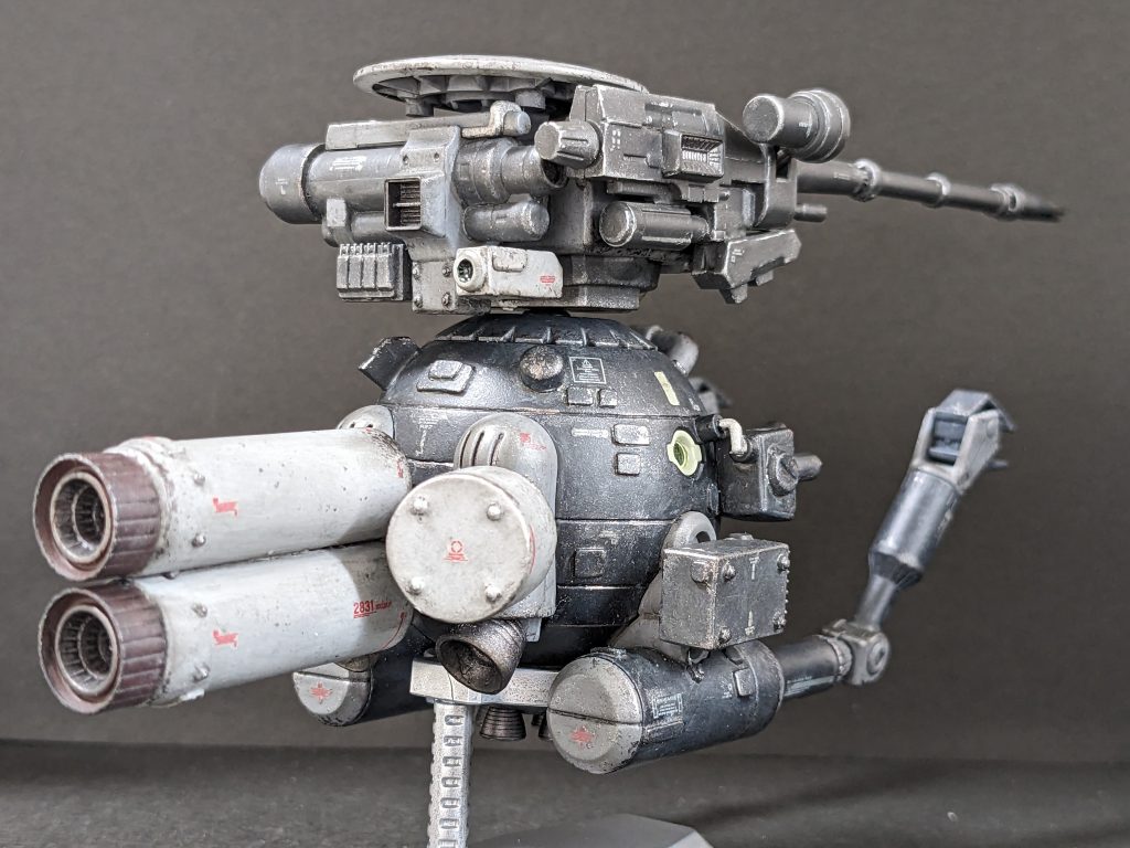 【背面】急速離脱用にバーニア付きのプロペラントタンクを設置。母艦からの単独長距離航行用に元々のバーニアにも短いタンクをそれぞれ追加。頭部ユニットには、離脱時の後方視界確保のためのカメラと、追手にばらまくための後方に向けたマイクロミサイルポッド。右翼のミサイルポッドも敵機破壊というより離脱時に弾幕目的。