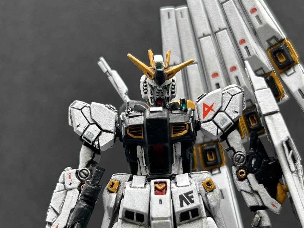 脚や腰の延長により、もともとのHIνガンダムの頭部が小さ過ぎてバランスがキャプテン翼のようになってしまったので、頭部を作り直しました。フルスクラッチではなく、横浜ガンダムの入場特典でもらえる小さいガンダムの顔を使用して制作。そのままだと逆に大き過ぎたので上下左右に幅詰めし、プラ板を貼って削り込んでνガンダムの顔になるよう作り込みました。頑張ったんですが自分の技術だとこれが限界でした😵