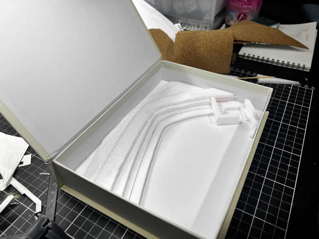 ジオラマです。ダイソーに売っている本の形をしたボックスをベースにしてジオラマと、ハイゴッグの下半身までは箱の中に収まり、蓋を閉じられるようにサイズを調整しました。ジオラマにしたい部分を地図から測量し、1/144にして下書き。それを元にスチレンボードで土台を作りました。