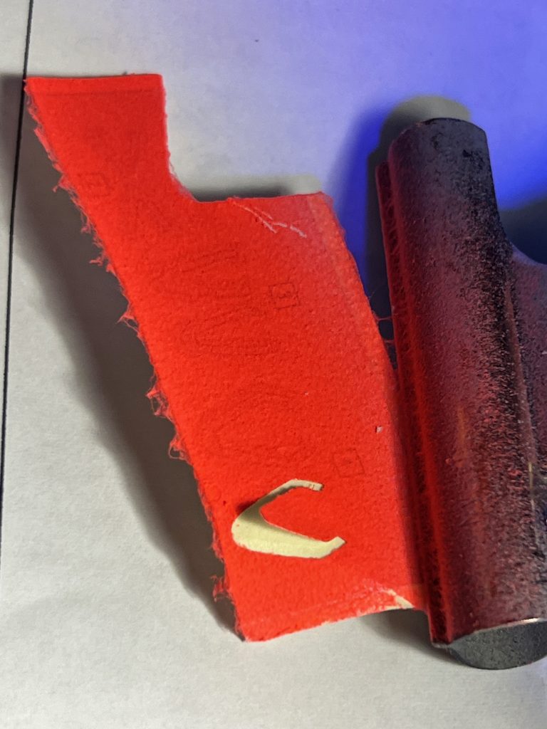 サフを吹いたシール台紙に蛍光レッドを数回にわけて吹きつけたところ。けばだっちゃいました