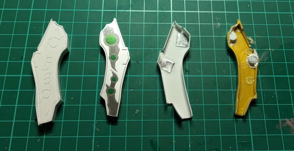 ルナティックアーチェリーの装飾部と切り出したプラ板の製作途中の1枚です。1.0㎜厚のプラ板で表面を切り出して0.3㎜厚プラ板を側面に貼り付け、装飾部を覆うようにしました。それだけでは保持力が足りないので、100均のネオジウム磁石とスチールプレートを接着してます。プラ板表面の淵を段落ちモールド化したら、表面をガンダムマーカーのホワイトゴールドとレッド、タミヤアクリルのクロームシルバー、側面をガンダムマーカーのシルバーで塗装しました。