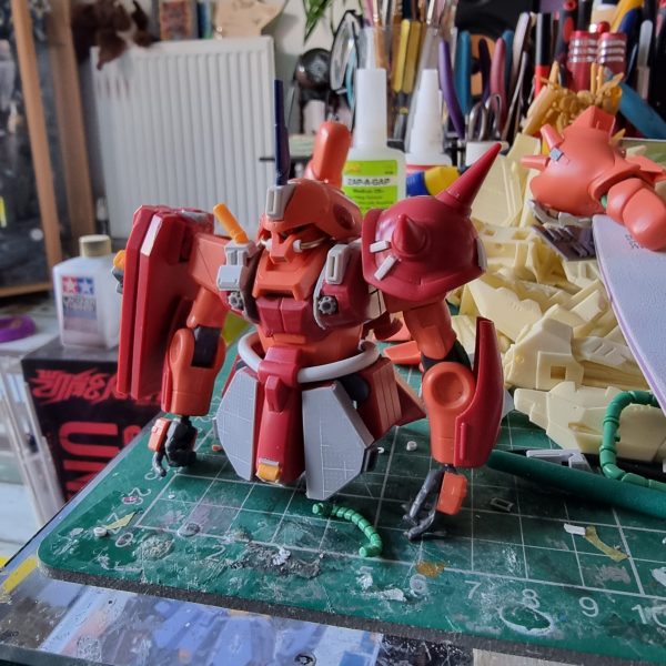 I want to realise the RX-107 Rosette from Advznce of Z in 1/144 scale. The base is HGUC kit. Here is the progress so far. I use AOZ Vol 4 for referance photo's as well as online sources.I began with the head, using parts from other AOZ kit's and brass rod. I used Dspiae plasicard to change shape of torso, and 3D printed the vents. The shield is magnetic so the amount back is held in place.Lots more work to do! （1枚目）