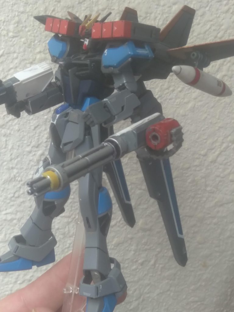 The left arm is equipped with a 105MM beam gatling gun with its own power supply. The shoulders mount 2 3-tube missile pods on each one