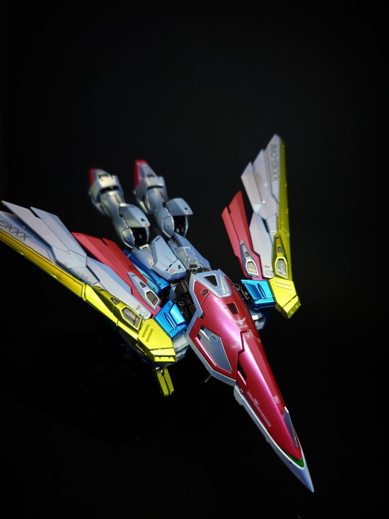 バード形態編集各スラスターのベクトルを後方へ集中させた[3]高速飛行形態。変形は全自動で行われ、空力特性が変化する。ACの世界では航空兵力として戦闘機が現役であり、MSを飛行戦用とした場合、エアリーズのように攻撃力が低下する機体も見られた[3]。本機の場合はバード形態を併用することで、戦闘機とMS双方の機体特性を獲得することに成功している[3]。変形後の戦闘力は従来型の戦闘機をしのぎ、大気圏突入も可能となる[5]。バスターライフルは機首（シールド）先端に装着され、その状態での発砲も可能[4]。第7話では、バスターライフルを装着せずにバード形態に変形する。EW版では腰は旋回せず、膝の折り畳み方向もテレビ版と逆になっている。