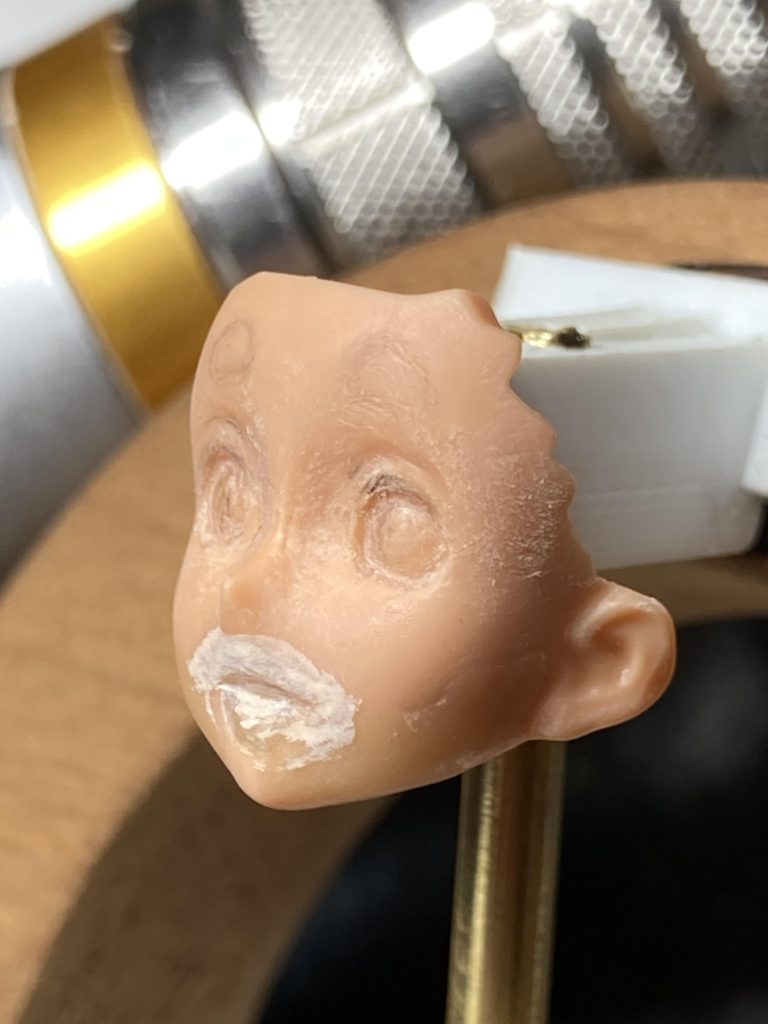 製作工程 2口の周りが白いのはサーフェーサー。口を埋めた紫外線硬化パテが半透明で、表面形状がつかみづらい為です。ほっぺの横にもパテが見えます。