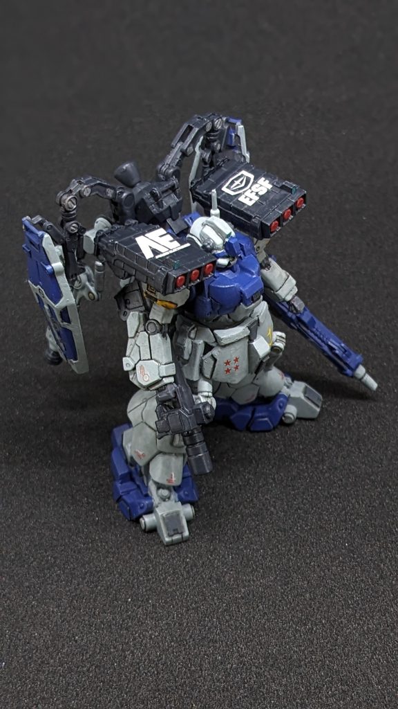 ガイツィク「あれが鹵獲したドムか?」メカニック「はい。損害は狙撃されたコックピットブロックだけのようですね。」ガイツィク「自分の部隊を逃がすためにしんがりで残ったようだが相手が悪かったな…」メカニック「でもこちらも3機やられましたからね。このドムも特別仕様だし腕の立つパイロットだったようです。」ガイツィク「おい。このドムのことは上層部に報告したのか?」メカニック「いえ。少佐が見にくるだろうと思ってまだ報告はしてません。」ガイツィク「よくやった。うるさいのが来る前に私のガレージに運ぶぞ!」メカニック「そう言うと思っていつものメカニック連中は集めておきました(笑)」ガイツィク「よし!今日から徹夜だ。2週間で仕上げるぞ。…と、その前にコックピットがミンチより酷い状態だろうからな…。私のガレージに運ぶ前に掃除しておけ!」