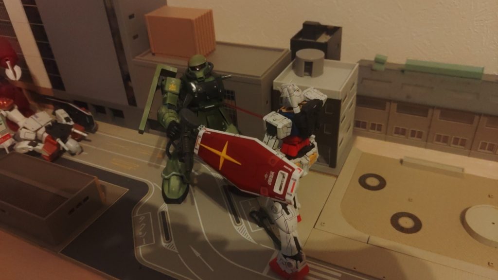 盾でヒートホークを弾き飛ばされ、腕を斬り落とされるザクさん