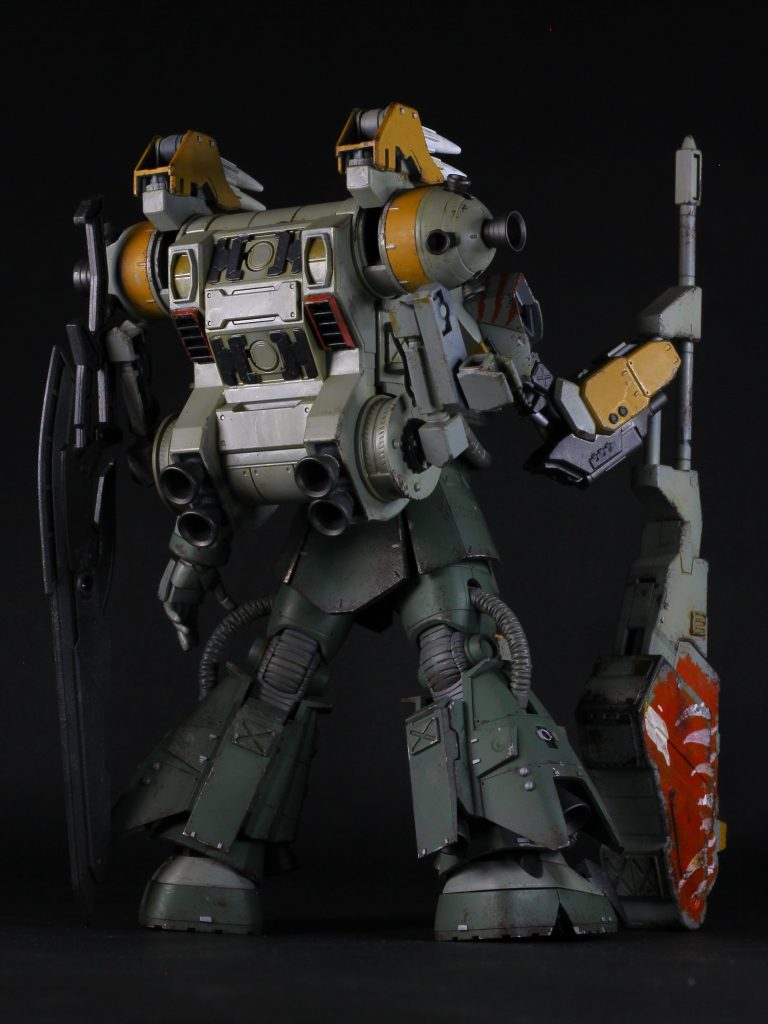 塗装は僅かに黒立ち上げで、チッピングメインの汚し(派手目)をしました。黄色い部分はシタデル、レンチメイスのアートはファレホを使った筆塗りです。ライトグレー部はクリアオレンジで墨入れしました。ブレード等のガンメタル部分は、シルバーやガンメタルをスポンジでポンポンして多層的に塗装しました。バックパックはサイコザクの物をベースに、コンパクトにしました。下側のスラスターをオミットしてウエポンラックに。肉抜きはパイピングで埋めました。サブアームがあった所には、バルバトス第五形態のミサイルを接続。